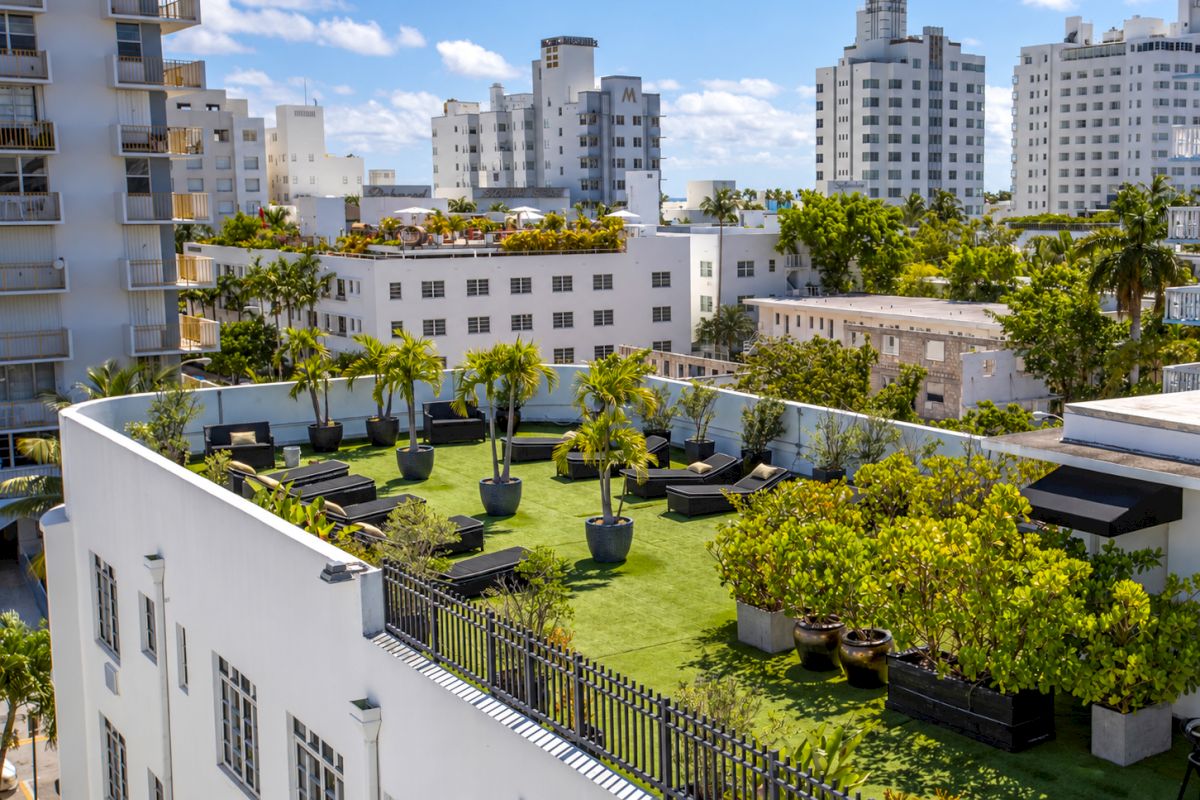 A rooftop lounge with green grass, trees, and lounge furniture overlooking the city.