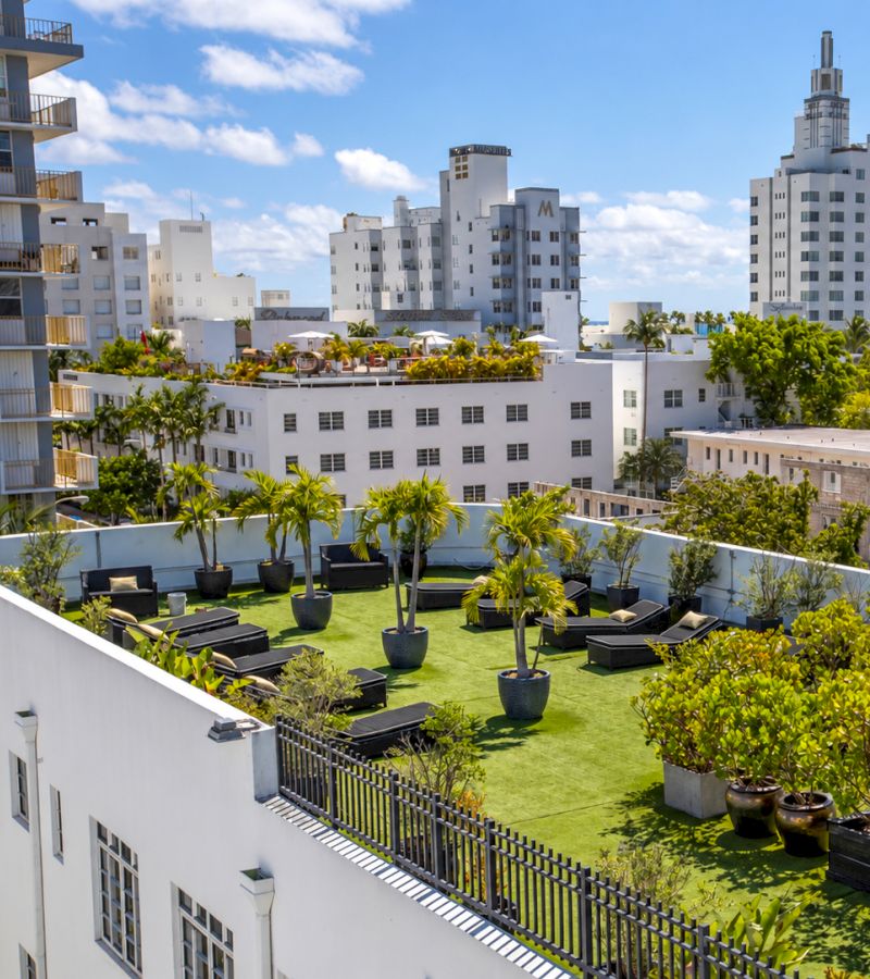 A rooftop area with artificial turf, potted plants, and seating areas.