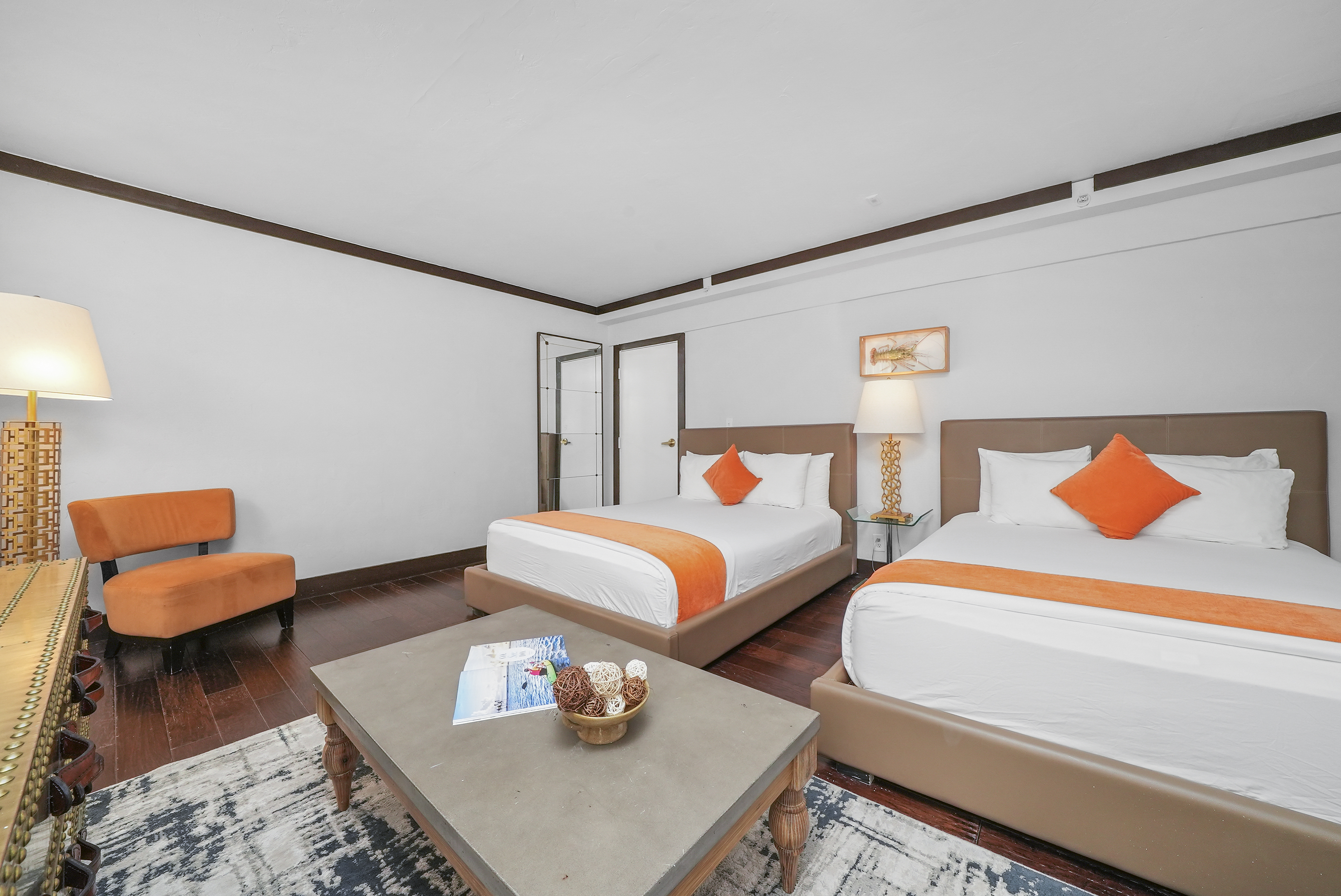 A hotel room with two beds, a coffee table, and a chair