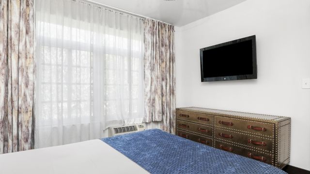 A hotel room with a bed, dresser, and TV.