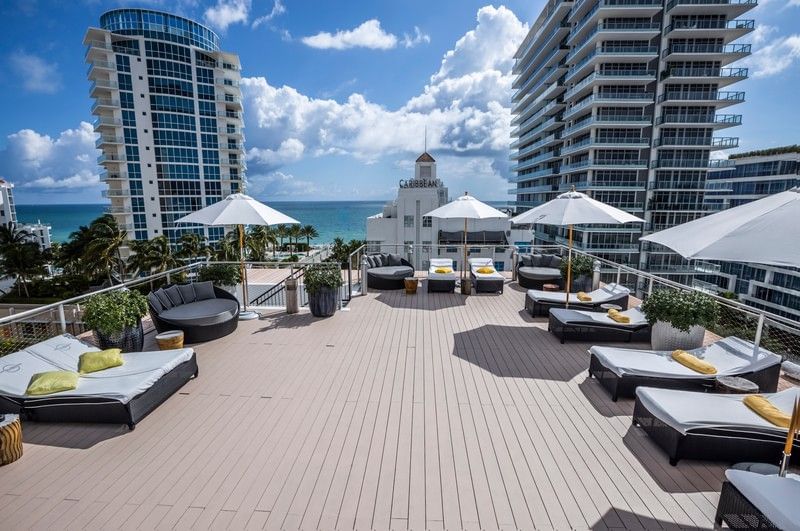 A rooftop pool deck with lounge chairs and umbrellas